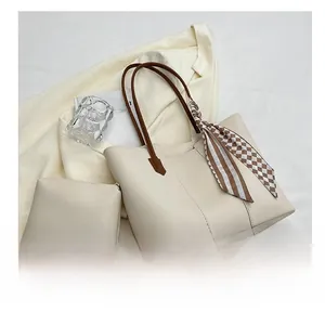 Detail of cream tote bag with brown leather handles, inner pouch and striped silk scarf