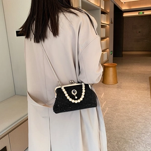 Elegante borsa da sera nera con perline, manico di perle e catena d'argento su modella