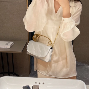 Chic silver satin shoulder bag featuring a unique oversized gold safety pin handle