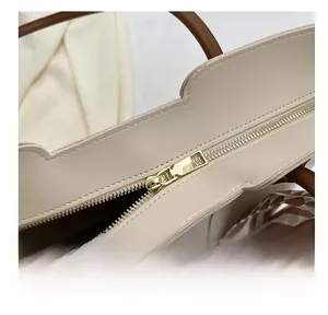 Detail of gold metal zipper and silk scarf wrapped on brown handle of beige tote bag