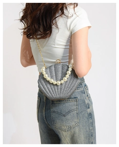 Detail showing shell-shaped crossbody bag with pearl handle and silver glitter texture