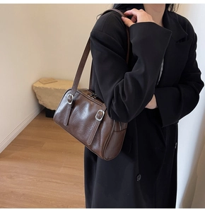 Détail du sac Boston vintage marron avec texture cuir brillant et boucles argentées