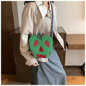 Detail of green apple-shaped crossbody bag with a melting red skull pattern design
