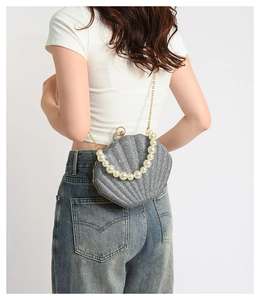 Detail of shell-shaped clutch bag featuring pearl handle and glittery silver texture