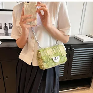 Close-up of green tweed crossbody bag with quilted pattern and metal chain strap