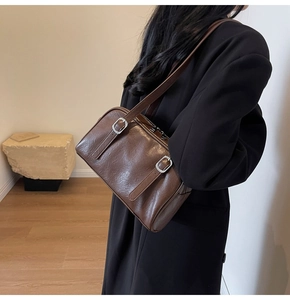 Gros plan sur un sac porté épaule en cuir marron foncé avec boucles argentées et détails rétro