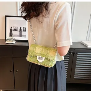 Close-up of green tweed crossbody bag with chain strap and metallic lock detail