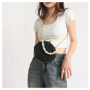 Detail of shell-shaped crossbody bag with sequins and elegant white pearl strap handle