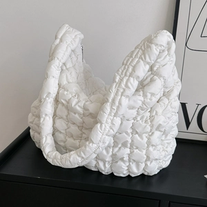 White quilted puffer tote bag with puffy cloud texture shown on a minimalist black surface