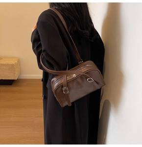 Détail du sac bandoulière en cuir marron foncé avec boucle argentée et texture vintage