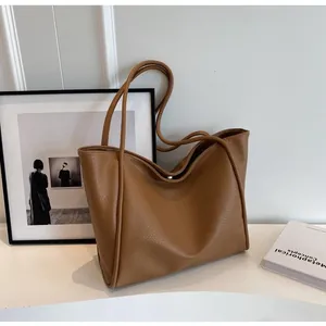Detailed view of brown litchi grain leather texture and magnetic closure on the tote bag