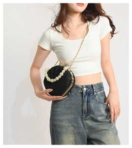 Detail of black sequined shell bag featuring a pearl handle and gold chain strap