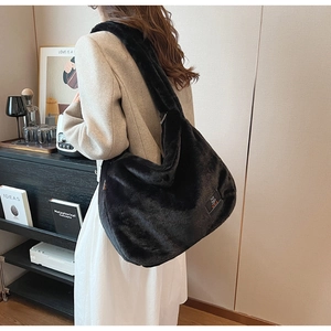 Détail du sac à épaule en peluche noire avec texture douce en fausse fourrure et étiquette