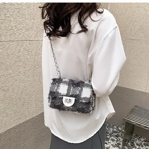 Detail showing tweed texture and metallic square lock on the black and white crossbody bag