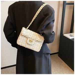 Détail du sac en tweed à chaîne dorée porté sur un blazer noir pour un style élégant