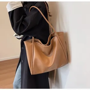 Minimalist large brown tote bag shown on model highlighting spacious capacity and pebble texture