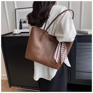 Detail of a large dark brown tote bag with a pink striped scarf on a shoulder strap