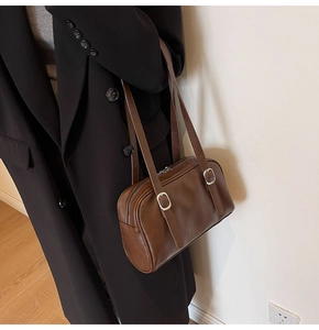 Gros plan du sac sous le bras marron vintage avec boucle argentée sur un manteau noir