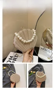 Detail view of shell-shaped handbag with sequins, large pearl handle and gold chain strap
