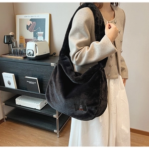 Gros plan d'un grand sac hobo en fausse fourrure noire avec de larges bretelles en peluche