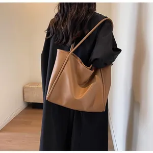 Close-up of large caramel tote bag with litchi texture on a model shoulder