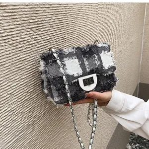 Close-up of quilted denim plaid bag featuring frayed edges and silver metal lock clasp