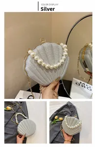 Detail of silver shell evening bag with pearl handle and metallic chain strap