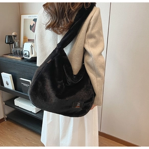 Détail d'un grand sac hobo en peluche noire avec texture fausse fourrure et étiquette ours