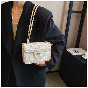 Détail d'un sac bandoulière en tweed blanc et beige avec fermoir doré et chaîne