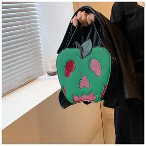 Detail of green apple-shaped shoulder bag featuring a red skull motif and leaf design