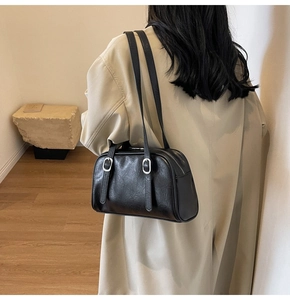 Détail du sac bandoulière en similicuir noir brillant avec longues anses et boucles argent