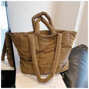 Detail of caramel quilted down tote bag showing padded handles and nylon texture