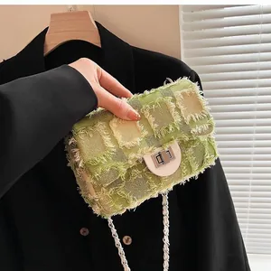 Detail of green tweed crossbody bag with silver twist lock and frayed edge texture
