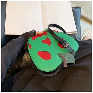 Detail of creative poison apple shaped shoulder bag with heart cutouts and leather strap