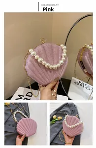 Close-up of pink shell-shaped sequin clutch bag with pearl handle and gold chain strap