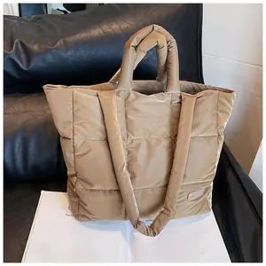 Close-up of khaki quilted tote bag featuring a leather fashion label on glossy nylon