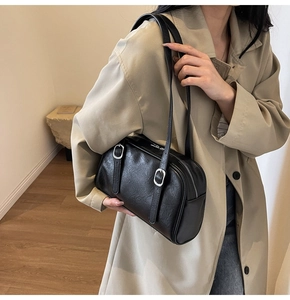 Détail du sac bandoulière noir avec boucles argentées sur un trench-coat beige