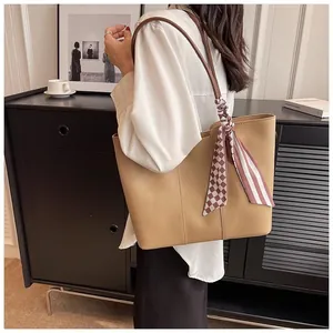 Detail of khaki tote bag with striped silk scarf and slim brown straps on a model
