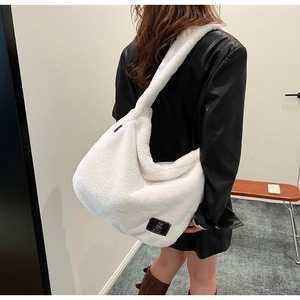 Gros plan d'un sac à bandoulière en peluche blanche avec un logo carré noir brodé