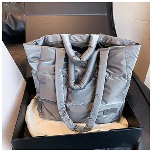 Detail of silver quilted tote bag with padded handles and fashion tag in gift box