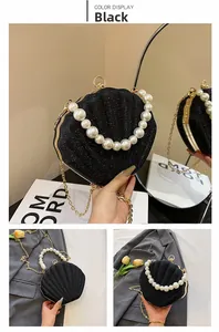 Close-up of black shell bag with glitter finish, pearl handle and gold chain detail