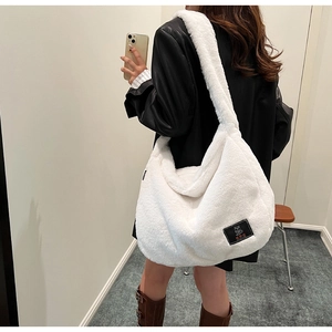 Vue détaillée du sac hobo en peluche blanche avec écusson de marque ours en peluche