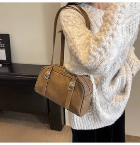 Détail d'un sac baguette vintage en cuir marron avec boucle en métal et fermeture éclair