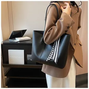 Black leather tote bag with decorative striped scarf on handle for office commuting