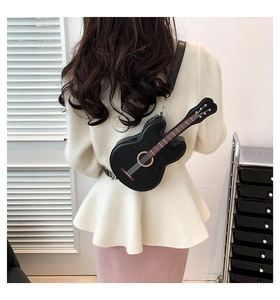 Detailed back view of a black violin-shaped crossbody bag worn by a model in casual attire
