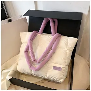 Macro view of quilted puffer tote bag with purple contrast handles in a black gift box