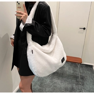Détail d'un sac à épaule en peluche blanche avec étiquette noire et grande capacité