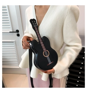Detail of a black guitar-shaped crossbody bag with realistic strings and silver zipper