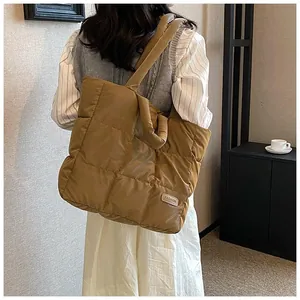 Detail of a large quilted down tote bag in brown with rectangular FASHION label