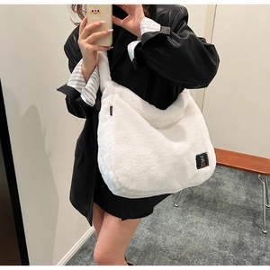 Détail du sac hobo en fausse fourrure blanche montrant la texture douce et le logo carré